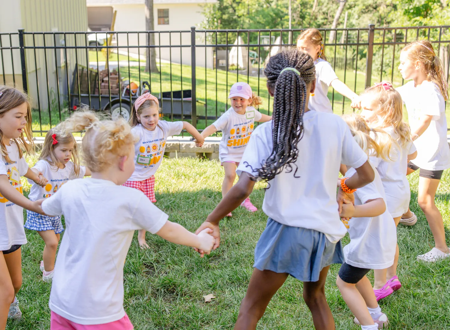 Neighborhood kids holding hands in a circle game in a backyard